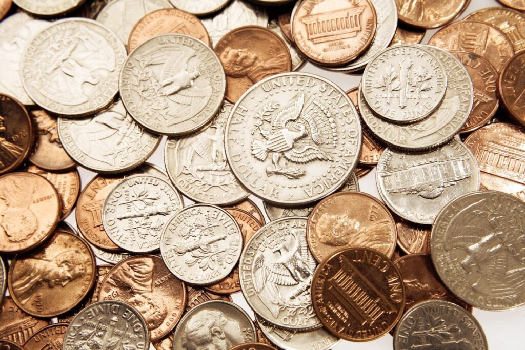 A close-up of assorted U.S. coins, including quarters, dimes, nickels, and pennies, scattered randomly.