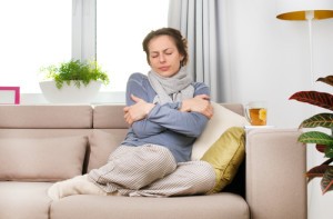 HELP heating repairs woman shivering sitting on couch in scarf