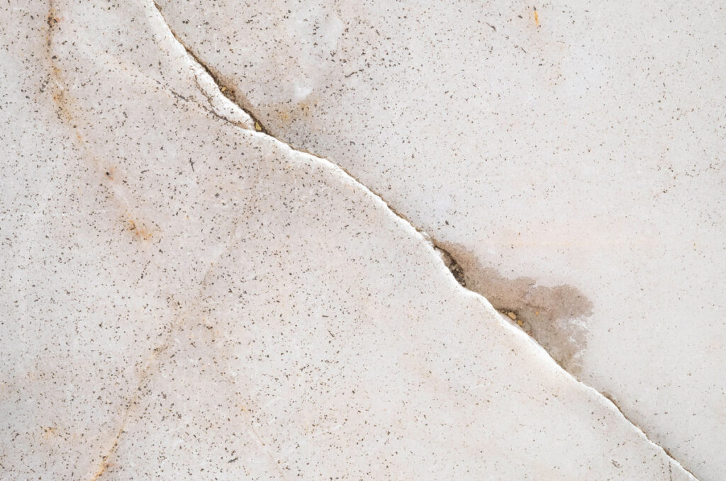 Detailed close-up of white marble showing natural cracks and light brownish stains, typical in areas serviced by HELP Plumbing.