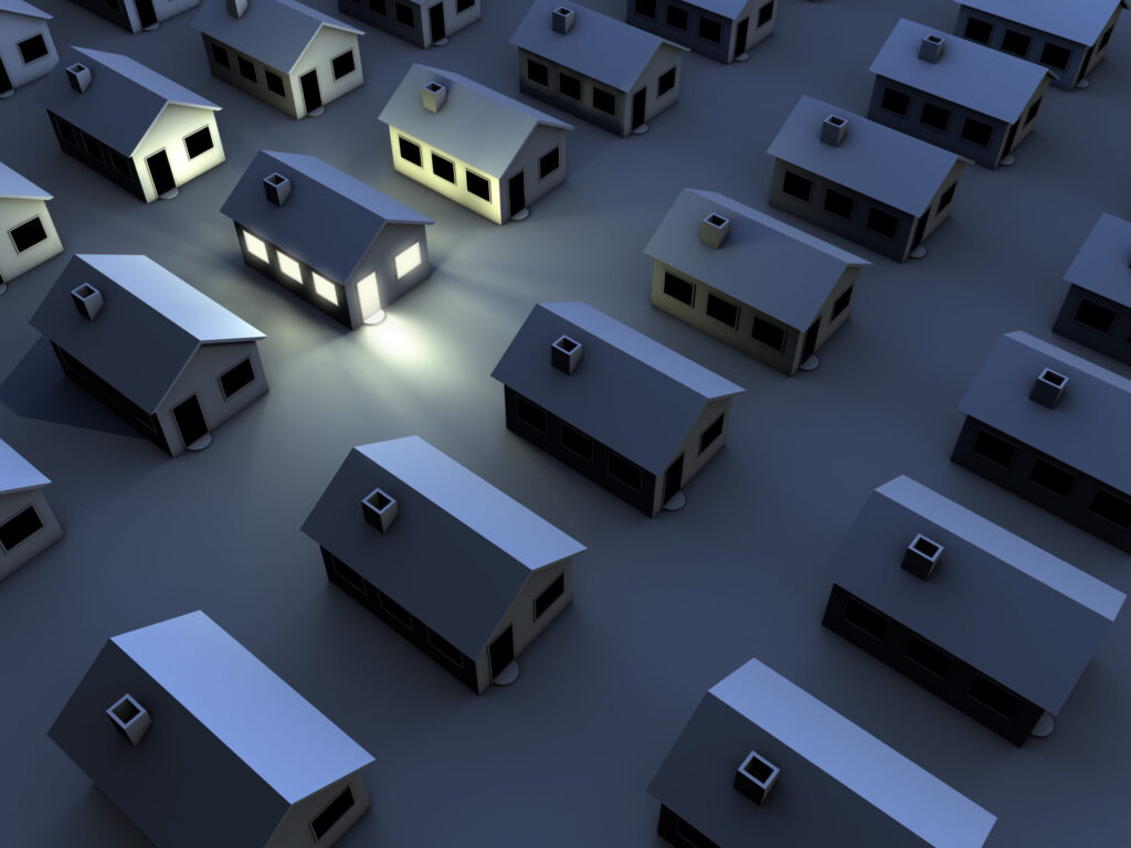 A row of similar homes at night, with one brightly lit house—highlighting a HELP Plumbing, Heating, Cooling and Drains customer.