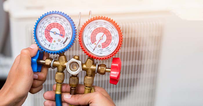 technician holding water pressure gauge in front of hvac system 