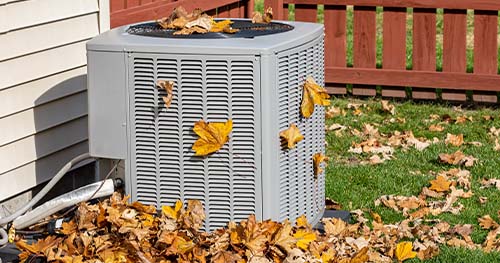 Image: an outdoor HVAC system covered in fallen leaves. For the best Corwin air conditioner services, call HELP.