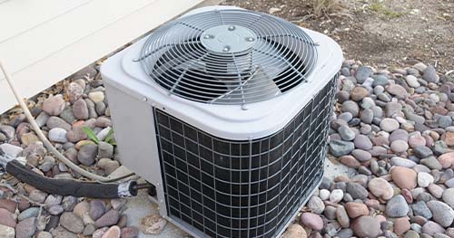 Image: a small condenser on a bed of decorative rocks. HELP provides the best Crosswick Air Conditioner maintenance and repair.