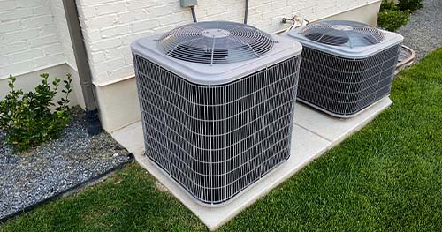 Image: two condensers side by side next to a house. Local homeowners trust HELP for Dayton air conditioner service.
