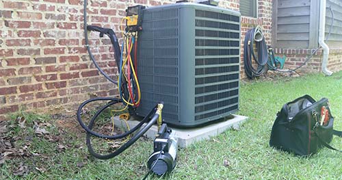 Image: an outdoor condenser is getting a tune-up. For the best Five Points air conditioner tune-ups, call the experts at HELP.