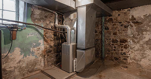 Image: an old furnace in a basement.